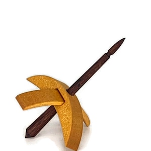 May include: A wooden spinning wheel with a gold finish. The wheel is made of two curved pieces of wood that are joined together at the top. The spindle is made of dark wood and is attached to the wheel.