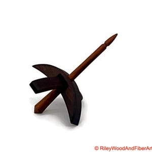 May include: A wooden drop spindle with a dark brown whorl and a lighter brown shaft. The whorl has a unique shape with curved edges and a central square. The shaft is pointed at the top.