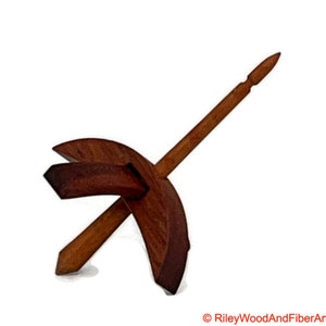 May include: A wooden spinning wheel with a brown spindle and a crescent-shaped base.