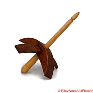 May include: A wooden spinning wheel with a brown base and a natural wood spindle.