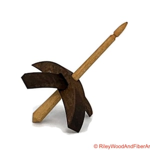 May include: A wooden drop spindle with a dark brown whorl and a light brown shaft. The spindle is designed for spinning fibers into yarn. The whorl has a unique shape with two curved arms and a pointed tip.