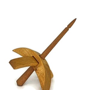 May include: A wooden spinning wheel with a spindle and a base. The wheel is made of light brown wood and the spindle is made of dark brown wood.