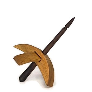 May include: A wooden spinning wheel with a dark brown spindle and a light brown base. The base is shaped like a crescent moon.