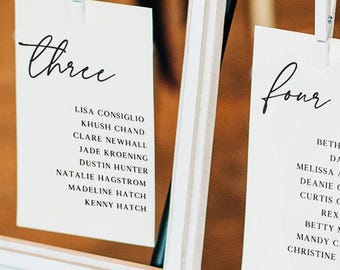 Puede incluir: Plano de asientos enmarcado en blanco con los números "tres" y "cuatro" en escritura elegante. Cada marco contiene una tarjeta con los nombres de los invitados, sujeta con una pinza. El fondo es de un tono cálido y neutro.