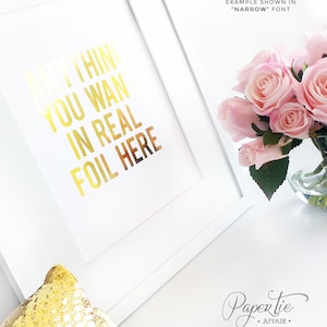 以下が含まれることがあります： 「ANYTHING YOU WANT IN REAL FOIL HERE」と金箔文字で書かれた白いフレームアートプリント。ピンクのバラの花束がガラスの花瓶に入っています。「EXAMPLE SHOWN IN 'NARROW' FONT」という文字がプリントの上にあります。