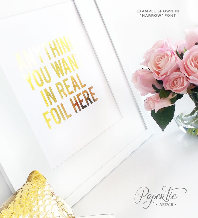 以下が含まれることがあります： 「ANYTHING YOU WANT IN REAL FOIL HERE」と金箔文字で書かれた白いフレームアートプリント。ピンクのバラの花束がガラスの花瓶に入っています。「EXAMPLE SHOWN IN 'NARROW' FONT」という文字がプリントの上にあります。