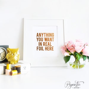 以下が含まれることがあります： 「ANYTHING YOU WANT IN REAL FOIL HERE」と銅箔で書かれた白いフレームのプリント。画像には、金のフクロウの置物、時計、糸巻き、ピンクのバラの花瓶も含まれています。