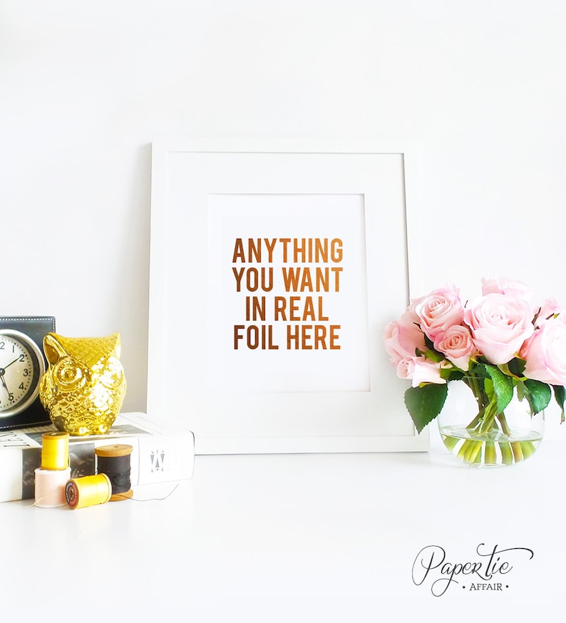 以下が含まれることがあります： 「ANYTHING YOU WANT IN REAL FOIL HERE」と銅箔で書かれた白いフレームのプリント。画像には、金のフクロウの置物、時計、糸巻き、ピンクのバラの花瓶も含まれています。
