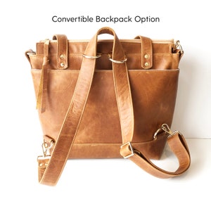 Puede incluir: Mochila convertible de cuero marr&oacute;n con correas ajustables y m&uacute;ltiples bolsillos. La bolsa tiene un asa superior y un cierre de cremallera. El texto "Convertible Backpack Option" es visible en la parte superior.