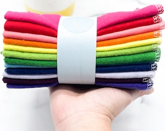 May include: A stack of 10 colorful cloths in a rainbow pattern, folded and bundled together with a white label that says "Golden Threads Co."