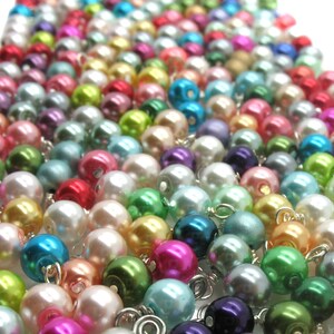 May include: A large assortment of colourful pearl beads, arranged in rows, with a variety of colours including pink, blue, green, and white.
