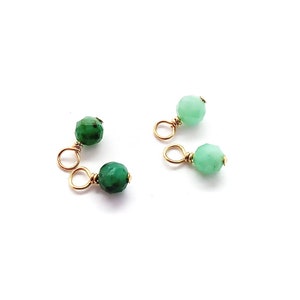 May include: Two pairs of gold-toned bead caps with green and light green gemstone beads. The bead caps have a loop on each end.