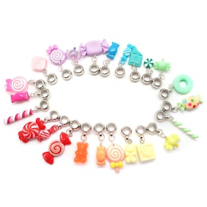 May include: A colorful charm bracelet featuring candy-themed charms, including lollipops, candy canes, gummy bears, and wrapped candies. The charms are attached to silver-toned beads.