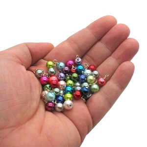 May include: A collection of colourful pearl beads with silver wire loops, ideal for jewellery making or crafting projects.