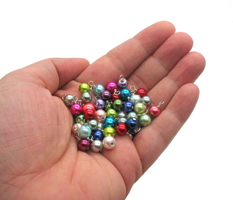May include: A collection of colourful pearl beads with silver wire loops, ideal for jewellery making or crafting projects.