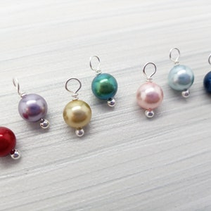May include: Seven pearl beads with silver wire loops, in colors red, lavender, gold, teal, pink, light blue, and dark blue.