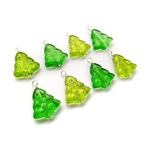 May include: Eight green and yellow glass Christmas tree charms with silver wire loops. The charms are in various shades of green and yellow.