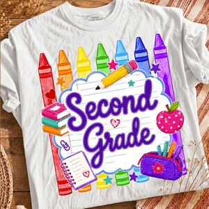 Peut inclure: Un t-shirt blanc avec une impression graphique représentant une feuille de papier ligné portant le texte Second Grade en écriture violette. Le motif inclut des crayons colorés, un crayon jaune, des livres, une pomme rose et une trousse violette.