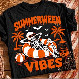 Peut inclure: Un t-shirt noir avec un motif représentant un squelette portant des lunettes de soleil, se relaxant dans une bouée rayée orange et blanche. Le design inclut des palmiers, des chauves-souris, un ballon de plage, un seau citrouille et le texte SUMMERWEEN VIBES.