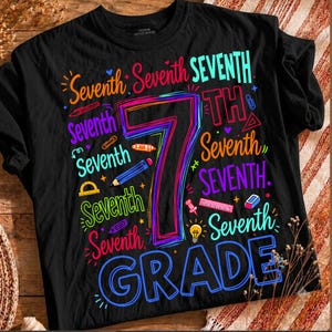May include: A black t-shirt featuring a large, colorful graphic with the text Seventh Grade. The design includes the word Seventh repeated in various fonts and bright colors, alongside illustrations of pencils, rulers, and a lightbulb.