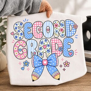 Peut inclure: Un t-shirt blanc avec le texte SECOND GRADE en grandes lettres bulles colorées et à motifs. Le design comprend des motifs vichy, rayures, pois et fleurs bleus et roses, agrémenté d'un nœud à pois bleu et d'un motif de crayon.