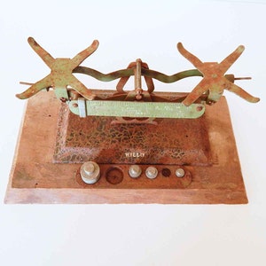 May include: A vintage, rusty, green metal balance scale with a wooden base. The scale has a ruler and a set of weights. The scale is labeled "WILO".