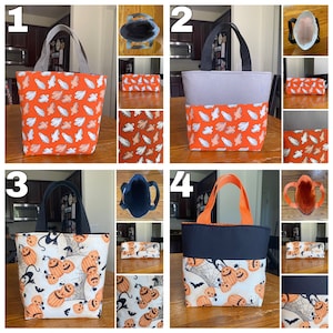May include: Four Halloween-themed tote bags with different designs. The bags are made of fabric and have a black or grey lining. The designs include ghosts, pumpkins, and bats. The bags are all approximately 20 cm tall and 15 cm wide.