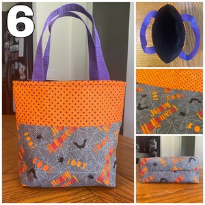 May include: A small purple-handled Halloween trick-or-treat bag with an orange and black polka dot fabric top and a gray fabric bottom with a spiderweb and bat pattern. The bag has the words "Happy Halloween!" printed on it.