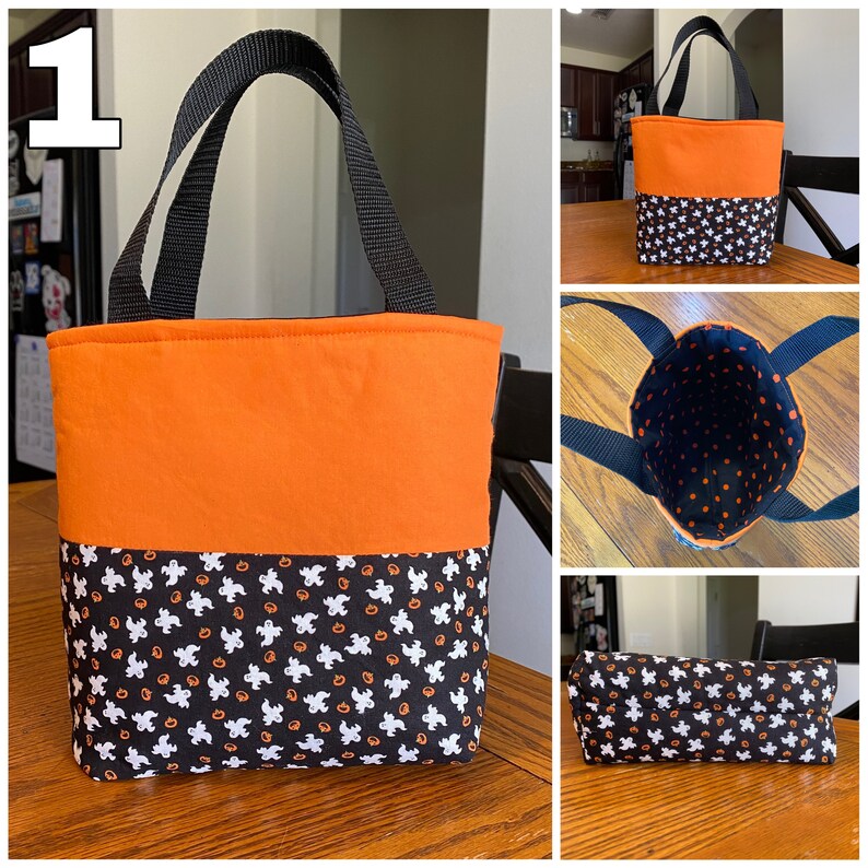May include: A small orange and black Halloween trick-or-treat bag with a black handle. The bag is made of fabric and has a pattern of ghosts and pumpkins on the bottom half. The bag is sitting on a wooden table.