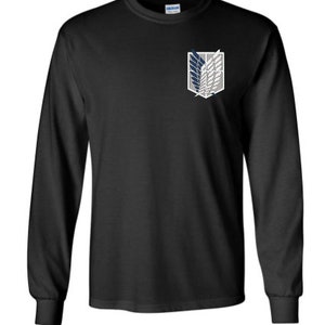May include: Black long-sleeve shirt featuring a white, gray, and navy blue emblem on the upper left chest. The emblem is a stylized design of wings. The shirt is made of a soft material.