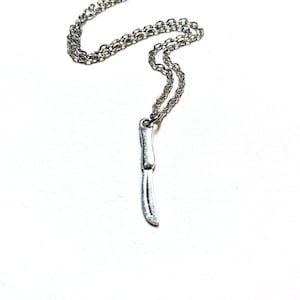 May include: A silver chain necklace with a silver knife pendant.