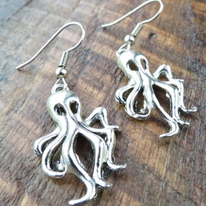 May include: Silver octopus earrings with a dangling design. The earrings have a hook closure.