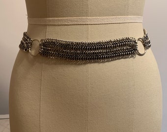 May include: A silver chain belt with multiple rows of chain links and two large circular clasps.