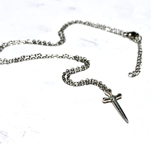 May include: A silver chain necklace with a small silver sword pendant.
