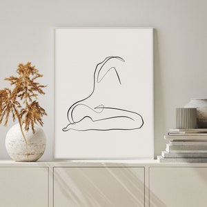 May include: A black and white line drawing of a person in a seated pose. The drawing is on a white background and is framed in a white frame.