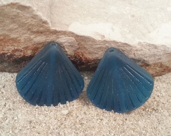 May include: Two blue glass shell-shaped beads with a textured surface.