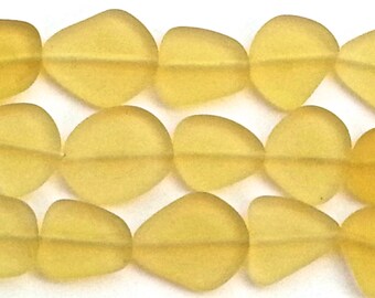 May include: A strand of yellow glass beads, each bead is shaped like a teardrop with a flat bottom. The beads are strung on a clear thread.