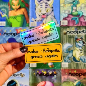 Puede incluir: Dos pegatinas rectangulares con el texto "make * neopets great again". Una es holográfica, la otra amarilla. Se sostienen frente a un fondo de revistas coloridas con temática de Neopets.