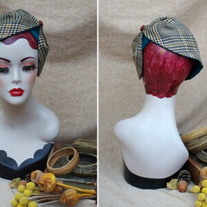 May include: A brown and black plaid hat with a teal blue trim and a brown button on top. The hat is on a mannequin head with red hair.