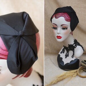 May include: A black satin hat with a bow on top. The hat is on a mannequin head with pink hair.