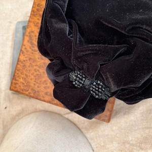May include: A black velvet bag with a black beaded embellishment.
