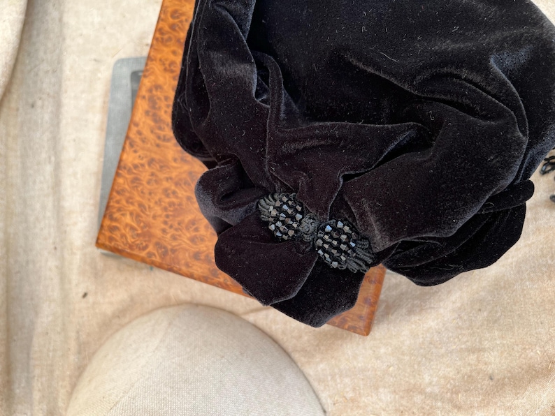 May include: A black velvet bag with a black beaded embellishment.