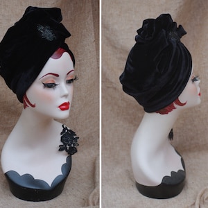 May include: A black velvet turban with a decorative embellishment. The turban is styled on a mannequin head.