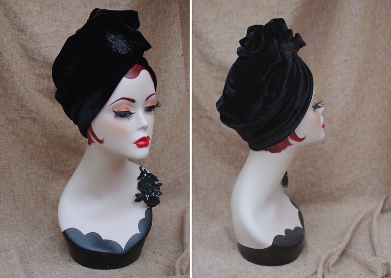 May include: A black velvet turban with a decorative embellishment. The turban is styled on a mannequin head.