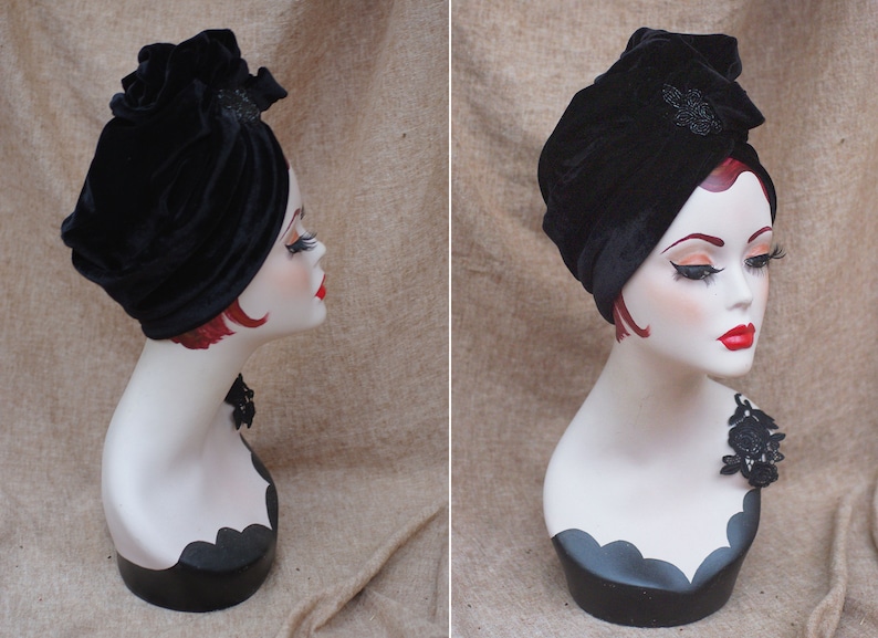 May include: A black velvet turban with a black beaded embellishment. The turban is worn on a white mannequin head.