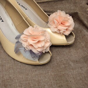 Peut inclure: Une paire de chaussures &agrave; talons beiges avec un bout ouvert et une d&eacute;licate fleur en embellissement sur chaque chaussure. Les fleurs sont de couleur rose clair et sont faites de tissu.