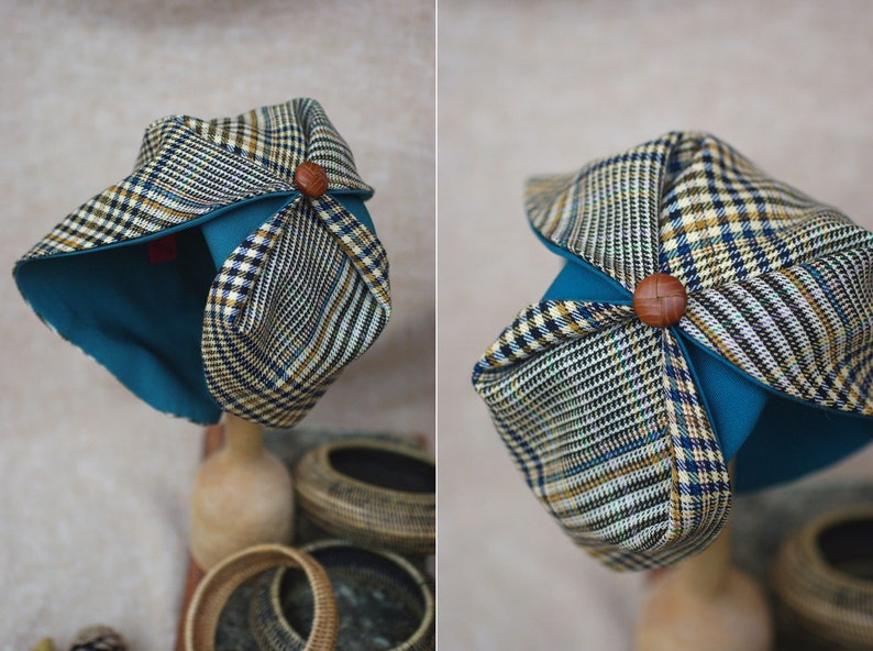 May include: A blue and brown plaid fabric hat with a teal lining and a wooden button on top.