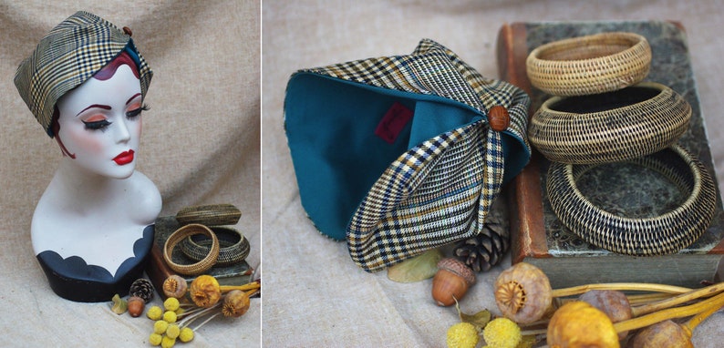 May include: A teal and plaid fabric turban with a wooden button. The turban is folded and displayed on a fabric surface with a book, acorns, and dried flowers.