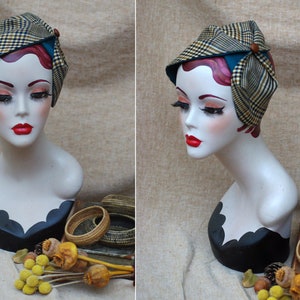 May include: A vintage-style hat with a plaid pattern in shades of brown, yellow, and blue. The hat is tied with a teal ribbon and has a brown button accent.