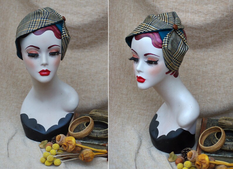 May include: A vintage-style hat with a plaid pattern in shades of brown, yellow, and blue. The hat is tied with a teal ribbon and has a brown button accent.